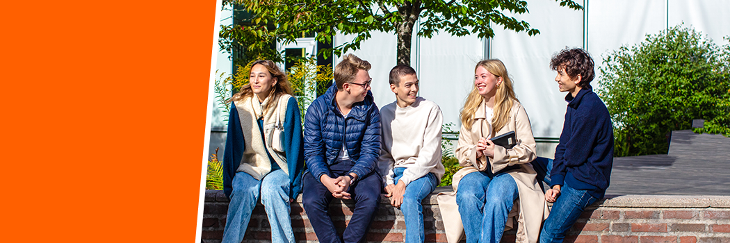 Glada elever på muren framför Östra gymnasiets framsida.
