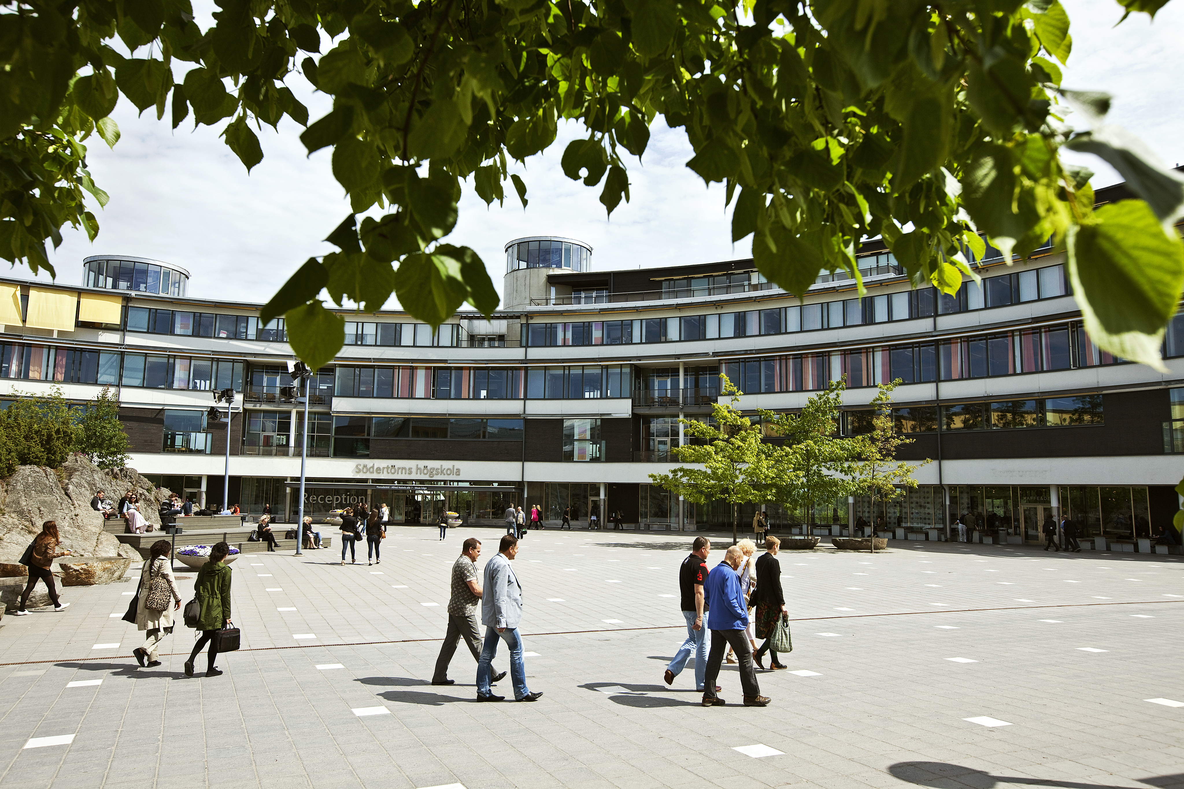 På bilden ser man campusmiljö från Flemingsberg, där studenter går över ett torg.