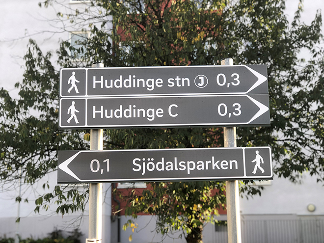 Skyltar för gående som visar väg och avstånd till Huddinge centrum, Huddinge station och Sjödalsparken.