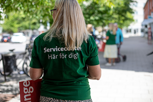 Ryggen på en grön t-shirt med texten "Servicecenter - vi finns här för dig". 