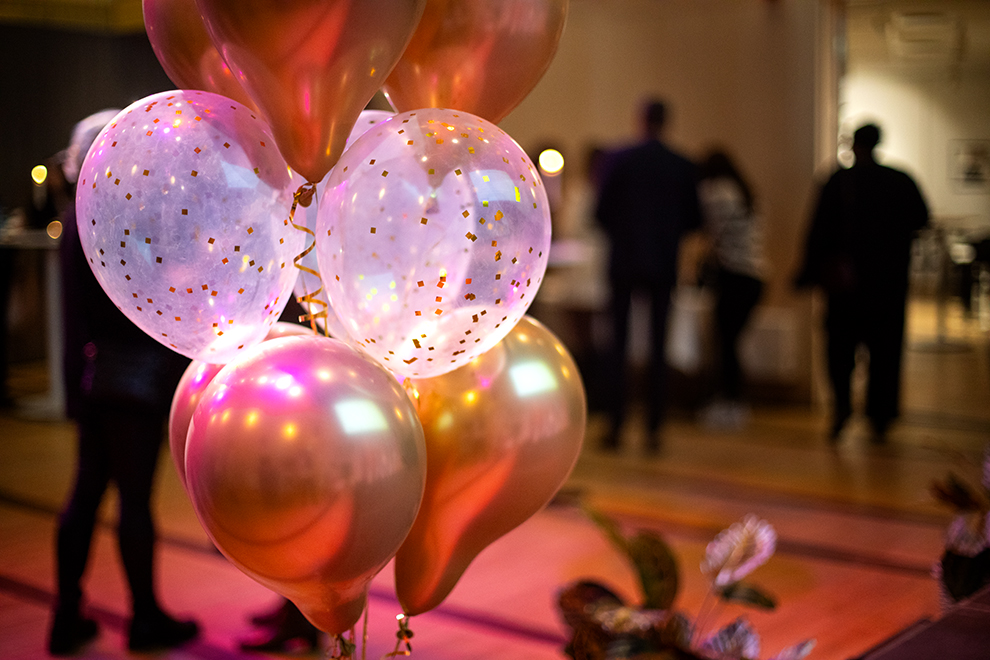 Ballonger och glitter i förgrunden, i bakgrunden människor i ofokus på  Huddinge kommuns kvalitetsgala 2024.