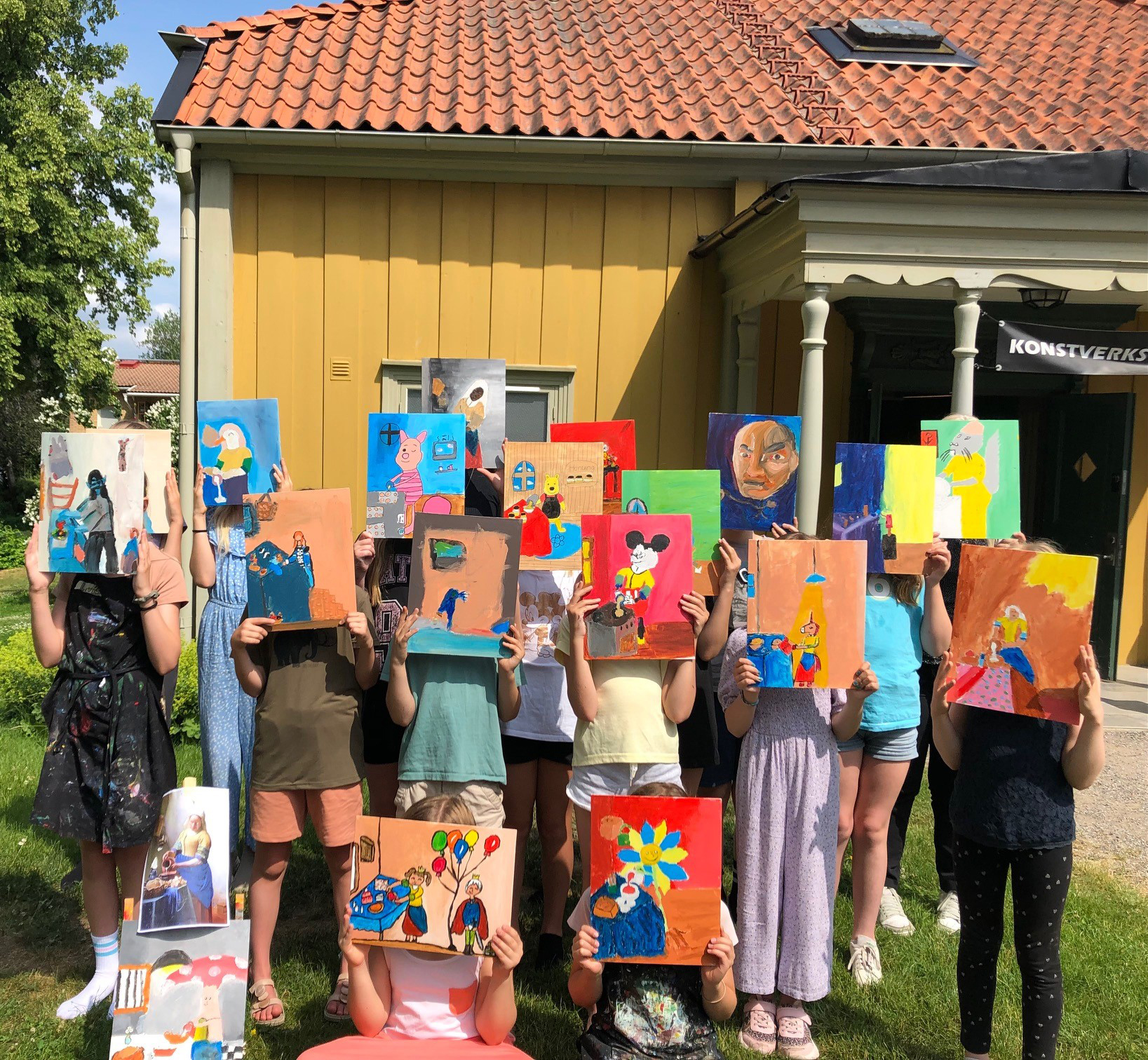 Barn som håller upp sina målningar.