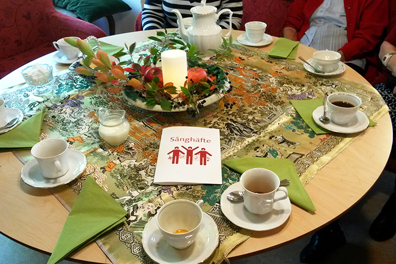 Kaffekoppar och ett sånghäfte på ett dukat bord.