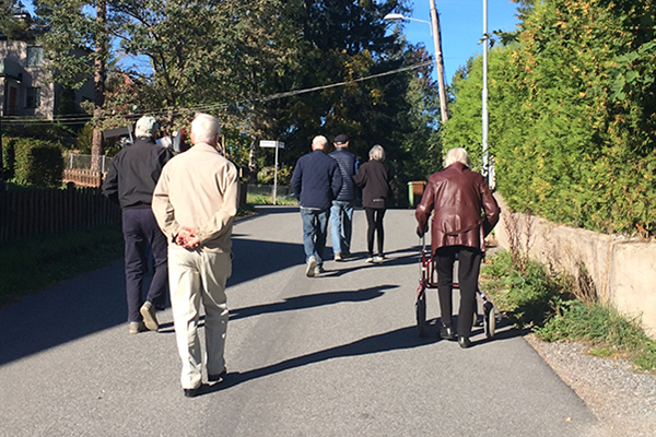 Några äldre personer går på promenad i solen.