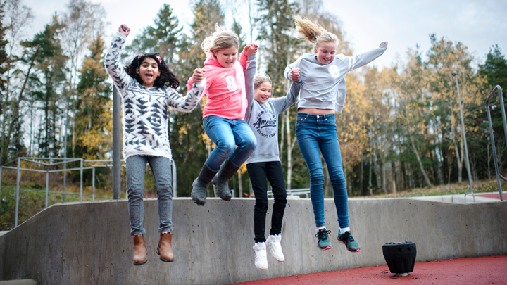 Fyra tjejer hoppar och håller händerna.